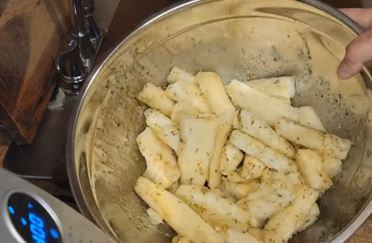 Adding spices and oil to the boiled yuca for air fryer yuca fries