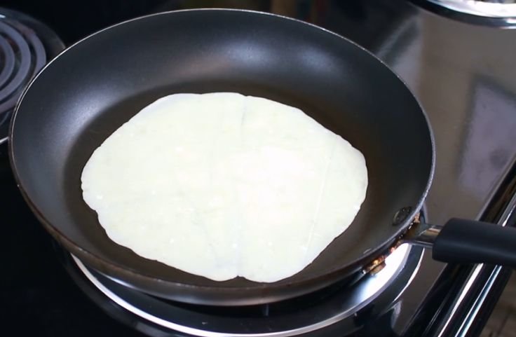 Placing the flattened dough into a heated skillet or pan and allow to cook