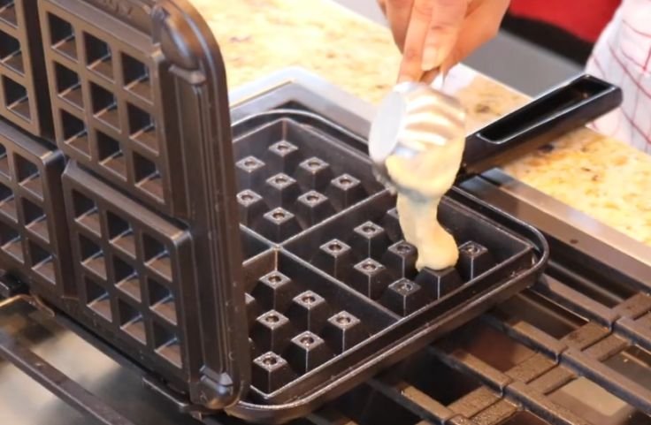 Measuring and pouring the waffle batter into the waffle compartments before cooking